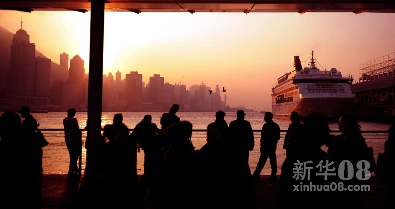 12月29日，游客在维多利亚湾畔欣赏日落美景。新华社照片，香港 新华社记者 陈晓伟 摄 2012年元旦和春节临近，来自世界各地的旅客涌进香港，掀起又一轮旅游购物热潮。截至12月21日，2011年抵港旅客人数已突破4000万人次。