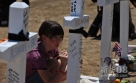 7月22日，少女基罗斯在悼念枪击案遇难者的十字架上写下祝福。新华社记者杨磊摄