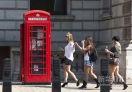 这是2012年5月28日，几名游客走过伫立在伦敦市中心一条大街上的红色电话亭。新华社/法新（刘昀编辑）