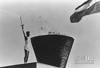 1964年8月21日，第18届东京奥运会圣火在奥林匹亚点燃。这次火炬接力采用海陆空三种传递方式，参与人数达十万。图为火炬手坂井义则点燃奥运会会场主火炬。新华社