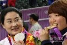 8月1日，韩国选手金蔷美（右）在颁奖仪式上咬金牌。当日，在伦敦奥运会射击女子25米运动手枪比赛中，金蔷美以792.4环的成绩获得夺金。新华社记者殷刚摄