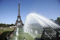 8月17日，在法国首都巴黎的埃菲尔铁塔前，人们在特罗卡德罗广场的喷泉下冲凉。高温天气近日袭击了法国六个省份，预计周末巴黎气温将达到36摄氏度。新华社/法新