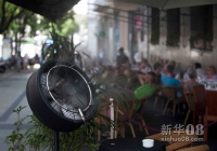 8月21日，在西班牙马德里，一家路边咖啡厅在电风扇上装置喷水设备，洒水降温。近日，新一轮热浪席卷西班牙，全国23个地区发布高温橙色警报，当日首都马德里最高气温达到41度。新华社记者谢海宁摄