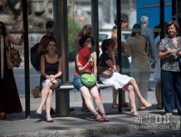  8月21日，在西班牙马德里，一名女子在车站等车时扇扇子降温。近日，新一轮热浪席卷西班牙，全国23个地区发布高温橙色警报，当日首都马德里最高气温达到41度。新华社记者谢海宁摄 