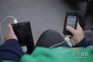 9月19日，在美国纽约第五大道苹果公司商店外，一名等待iPhone5手机上市的男子用便携充电器为手机充电。新华社/路透  