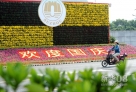  9月24日，一名市民从江苏省苏州市街头的国庆布景花坛旁经过。 随着中秋、国庆“双节”临近，古城苏州花团锦簇，到处洋溢着浓浓的节日氛围。  新华社发（杭兴微 摄） 