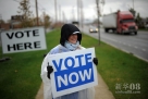 10月15日，在美国俄亥俄州哥伦布市，一名民主党的志愿者手持总统大选提前投票的告示牌。新华社/法新