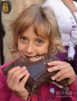 10月21日，在意大利中部山城佩鲁贾，一名小姑娘啃着一大块巧克力现场雕塑活动分享的碎片。新华社记者王庆钦摄 