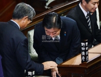 11月16日，在日本首都东京，首相野田佳彦（中）在众议院全体会议会场向一名议员致意。新华社/法新