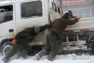 12月4日，在东方红的街道上，人们在推一辆陷在雪里的卡车。新华社记者王凯摄  