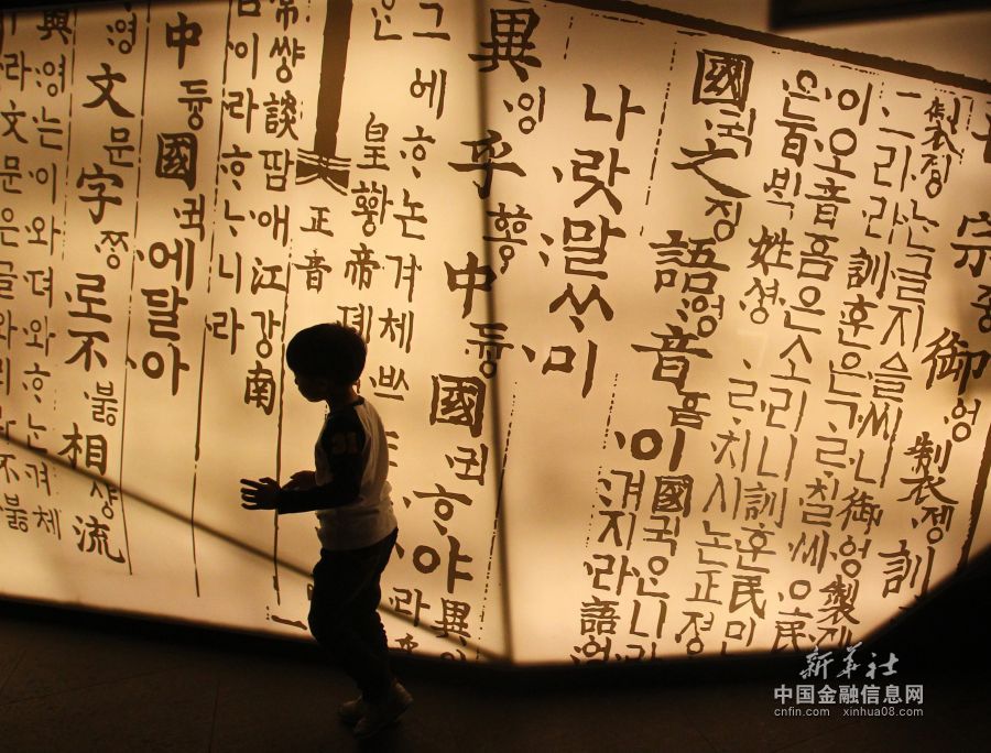这是一名韩国小朋友从首尔一座写满汉字和韩文的幕墙前走过(2013年10月9日摄)。在1443年世宗大
