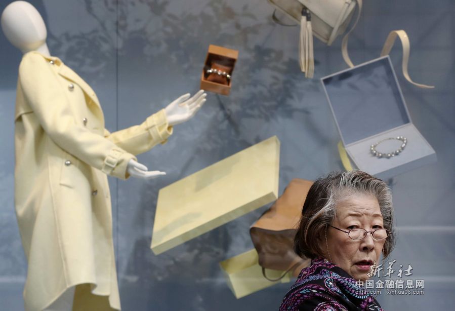 11月16日，在日本东京银座商业区，一名女子走过一家奢侈品店的橱窗。新华社/路透  