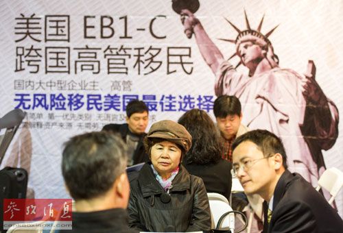 资料图片：2013年4月11日，一家公司工作人员在北京春季房展会向参观者介绍海外投资移民情况。