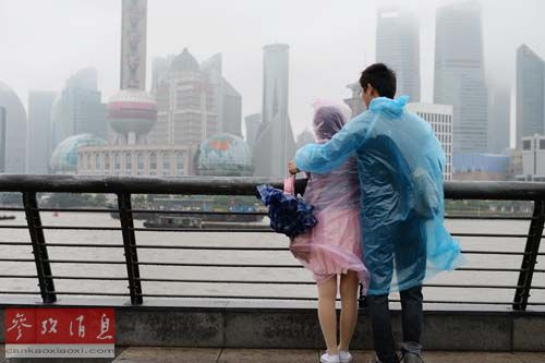 资料图：一对穿雨衣的情侣在上海外滩观光平台观景。新华社发（赖鑫琳 摄）
