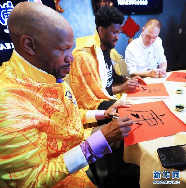 2月15日，传奇球星罗恩·哈珀（左）和NBA费城76人队球星恩比德（中）练习中国书法。新华社记者李颖摄