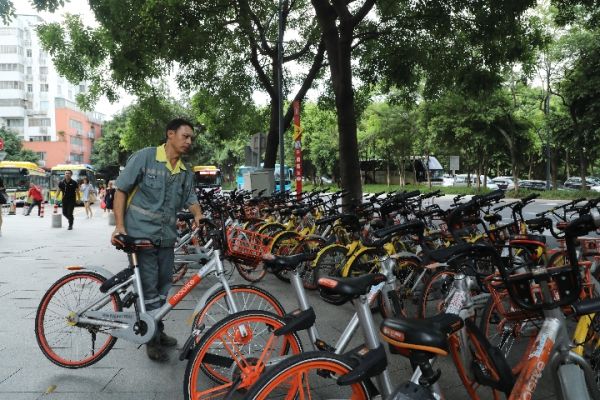 广州市天河区科韵路，路边停放的共享单车占据了大半条人行道，一名环卫工人将单车摆放整齐。 新华社记者李嘉乐摄