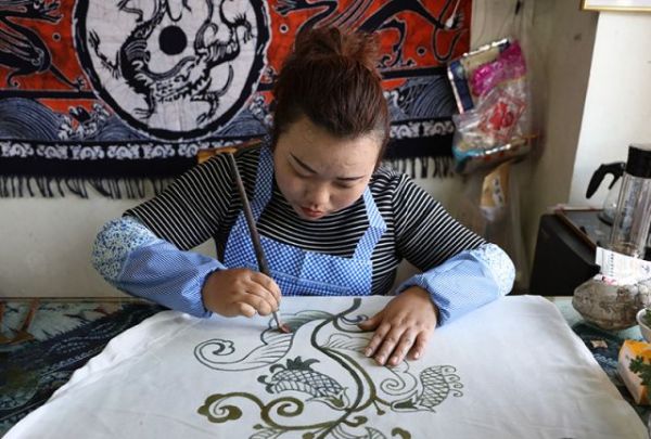 图为苴兰蜡染设计者在绘制，蜡染被称为中国古代三大印花技艺之一。