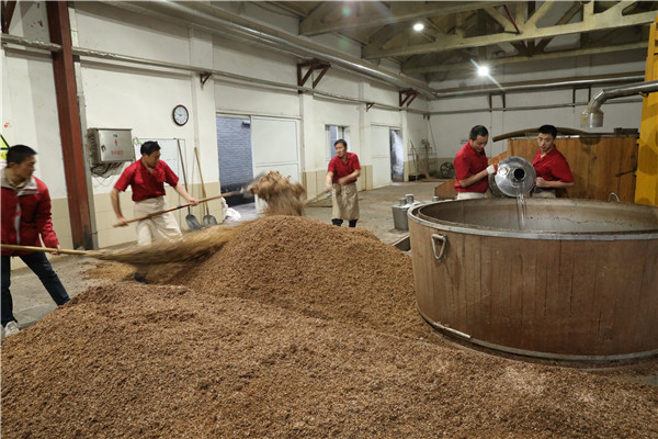 在古法酿酒工艺中，工人们需要往甑桶里灌入水，准备蒸馏酒体。（席航飞 摄）