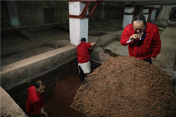 工人们在高沟老窖里挖出酒醅，吴建峰（右）在细细品嗅酒醅的香气。（席航飞 摄）