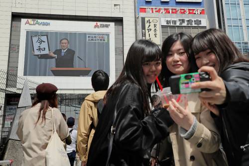 4月1日，在日本东京，行人在观看关于日本公布新年号的新闻节目时自拍。