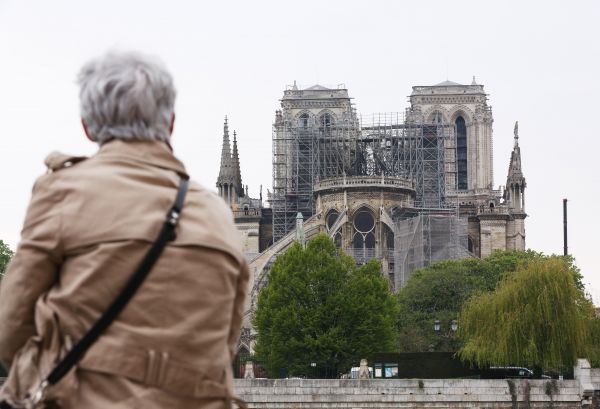 4月16日，在法国巴黎，一名老妇人在塞纳河畔望着“受伤”的巴黎圣母院。（新华社） 