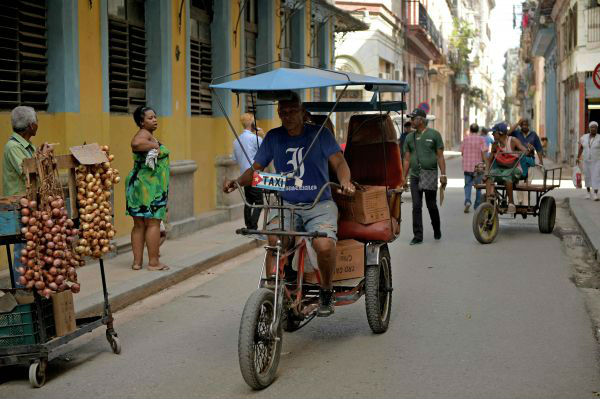 资料图：一名三轮车夫在古巴哈瓦那街头寻找生意。