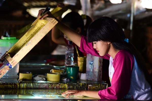 在印度尼西亚唐格朗市的一家蜡烛工厂，女工在蜡烛外包装上印刻文字和图案。 （新华社）