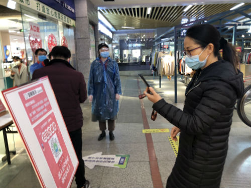 2月19日，顾客在进入南宁一家超市前扫码登记。