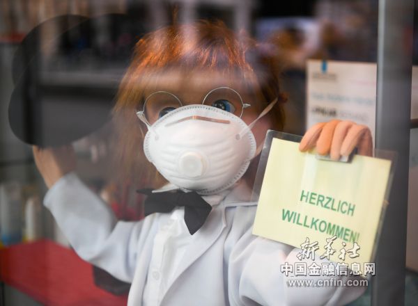 3月8日，在德国法兰克福，一家药店门口摆放着戴口罩的卡通人偶。