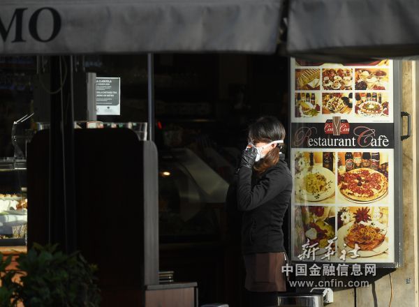 3月10日，在意大利米兰，一名戴口罩的女子站在关闭的餐馆前。