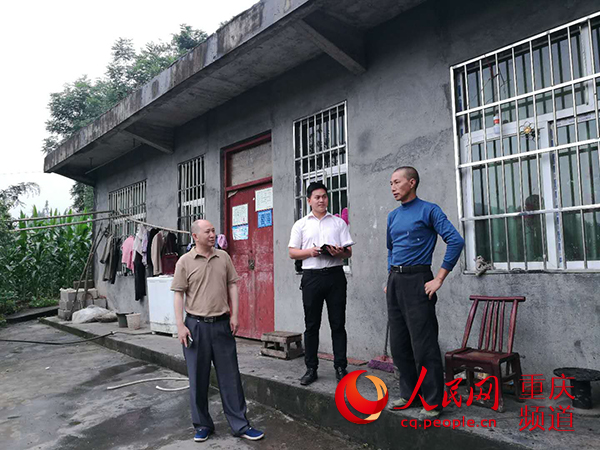 费明江（左二）和驻村工作队员一起入户走访。邮储银行重庆分行 供图