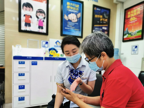 建行成都第六支行，大堂经理为客户介绍手机银行“大字”模式